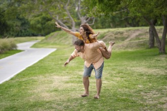Man giving his girlfriend a piggyback ride in a park