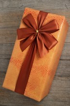 Beautifully decorated gift box with bow on wooden background