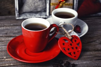 Red mug with black coffee and two carved decorative wooden heart.selective focus