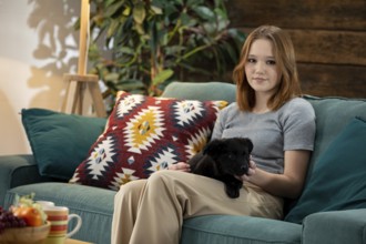 A young woman happily enjoys quality time with her adorable puppy in a stylish and inviting living