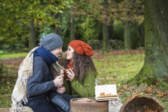 Loving young couple sitting in the autumn garden