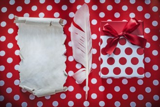 Present box vintage sheet of paper plume on polka-dot red table cloth celebrations concept
