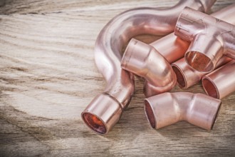 Copper water pipe connectors on wooden board plumbing brassware concept