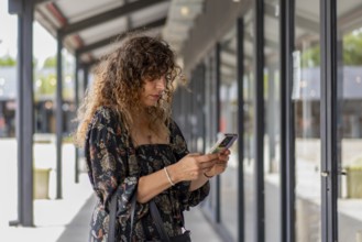 Trendy woman using her smartphone while strolling in a modern shopping district