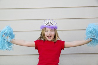 Blond kid girl playing like cheerleading pom poms with princess crown