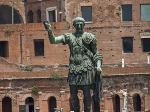 Bronze statue of a soldier in front of an ancient building in sunny weather, Rome, Italy, Europe