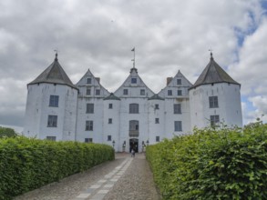 An impressive white castle with several turrets under a cloudy sky, glücksburg, schleswig-holstein,