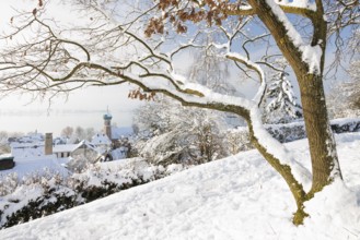 A snowy village with houses and a church tower of St. Nicholas, winter atmosphere, peaceful,