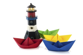 Colorful folded paper boats with lighthouse isolated over white background