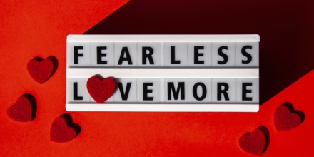 Lightbox with text FEAR LESS LOVE MORE. Motivational Words Quotes Concept with red hearts. Colorful