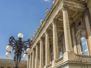 A building with classical columns, decorated with an ornate street lamp and blue sky in the