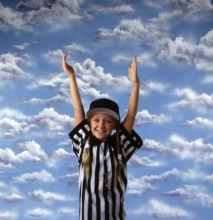 Smiling girl in referee outfit with hands raised against a vibrant sky, expressing joy and