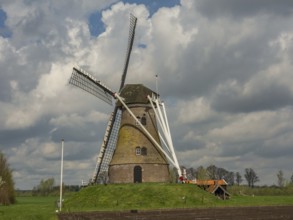 A historic windmill stands on a green meadow under a cloudy sky, Eibergen, Gelderland, Netherlands
