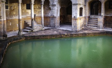 Water and buildings in an old roman bath in the city of Bath in the united kingdom england