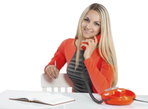 Beautiful smiling young businesswoman talking with phone at the table isolated