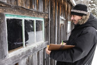Middle aged home Inspector taking notes on a notebook with leather cover during an outdoor