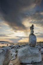 Stone sculpture on the shore of a lake at sunset with dramatic sky, Seegarten, Allensbach, Lake