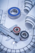Rolls of construction drawings round rolling bearings and trammel caliper on blueprint industrial