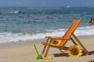 Empty beach chair with flowers and toys at the sea