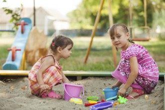 Two girls play in the sandbox at the playground