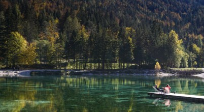 Kranjska Gora, Slovenia, 18 October, 2021: tourists enjoy relaxing on the wooden dock at Lake Jasna