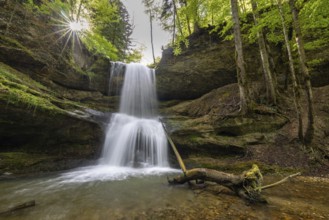 Waterfall with in the forest, where the sun rays penetrate through the trees, forming a peaceful
