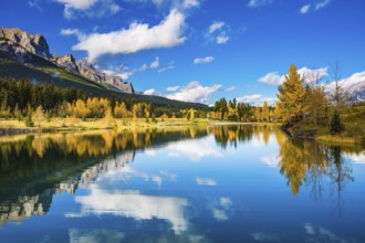Concept hiking. Canmore, near Banff. Jagged mountains and red-orange trees are reflected in the