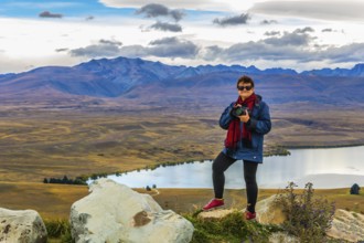 Woman photographer on the mountain. Exotic journey to the South Island, New Zealand. Concept of