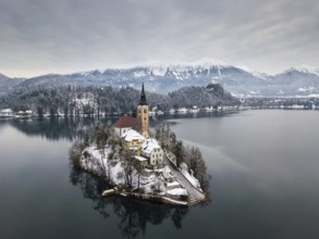 Aerial shot of lake Bled on a calm winter morning with snow
