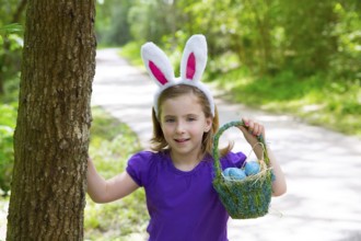 Easter girl with eggs basket and funny bunny ears on the forest