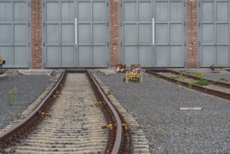 Empty rails lead to large grey doors on gravel, bochum, westphalia, germany