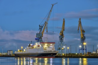 Three yellow and blue cranes at dusk in the harbour of Belfast, Northern Ireland