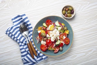 Greek fresh healthy colorful salad with feta cheese, vegetables, olives in blue ceramic bowl on