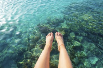 Ibiza girl legs at Portinatx beach pier clear water in Balearic Islands