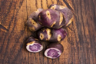 White - violet potato on wooden background. Organic plant