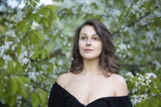 Close-up of a woman surrounded by green leaves and white blossoms