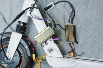 Electric scooter with exposed components and wiring, showcasing mechanical details on a grey