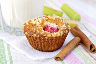 Cupcake with rhubarb, cinnamon on a white paper napkin, rhubarb, milk in a glass on a background of