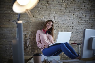 Businesswoman young casual sitting at office working with laptop computer feet on table relaxed