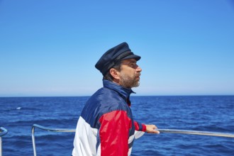 Beard sailor man sailing sea ocean in a boat with captain cap looking horizon