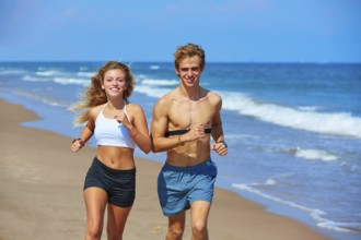Blond young couple running on the beach in summer vacation