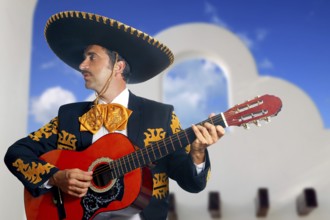 Charro Mariachi singer playing guitar in Mexico with white house background