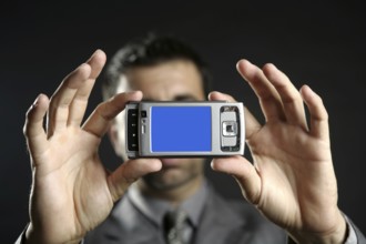 Businessman taking photos, mobile camera, black background