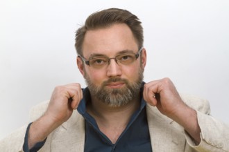 Man straightens his shirt collar - on a light background