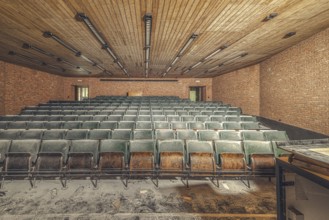 Dusty, empty lecture theatre with green rows of seats and visible bricks, Institute of Molecular