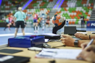Ball on the referee's table and handball match in the background
