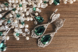 Earrings with a large emerald and an ornament of white beads on a brown background with a rough