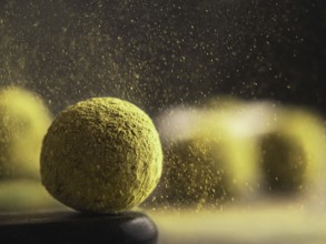 Homemade truffles candy with matcha tea powder in green tea dust cloud over dark background. Copy