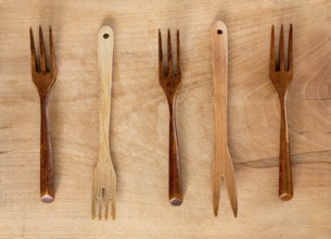 Wooden forks on a wooden background from above. Studio shot. Kitchen utensil