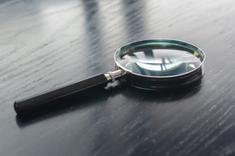Magnifying glass on top of black wooden table top